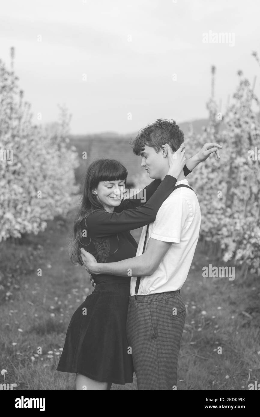 Jeune amour fort entre deux jeunes marchant sous des pommiers. Portrait franc d'un couple en vêtements décontractés. Affection de deux personnes. Noir an Banque D'Images