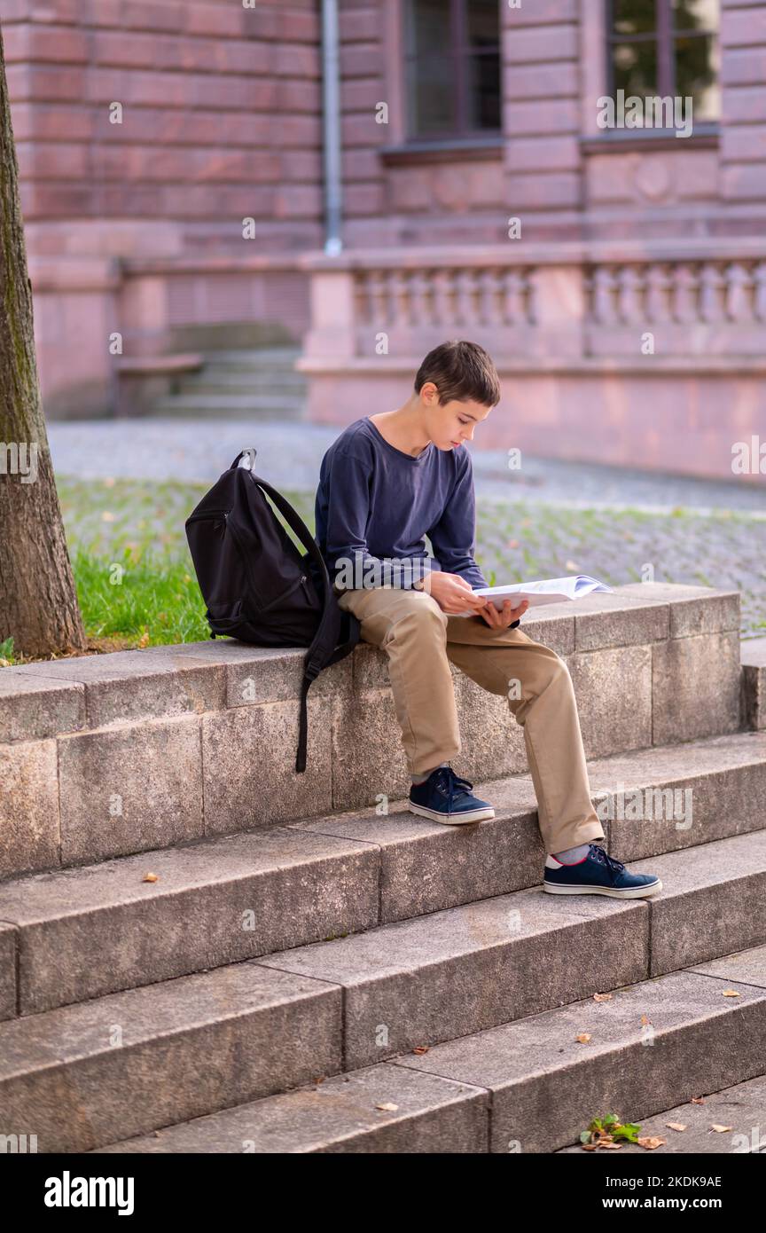 Jeune garçon ciblé lisant un livre à l'extérieur Banque D'Images