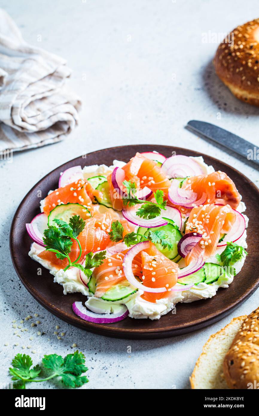 Plateau de beurre avec saumon salé, concombre, radis et coriandre sur une assiette en bois pour bagel. En-cas de fête, tendance à la cuisine. Banque D'Images