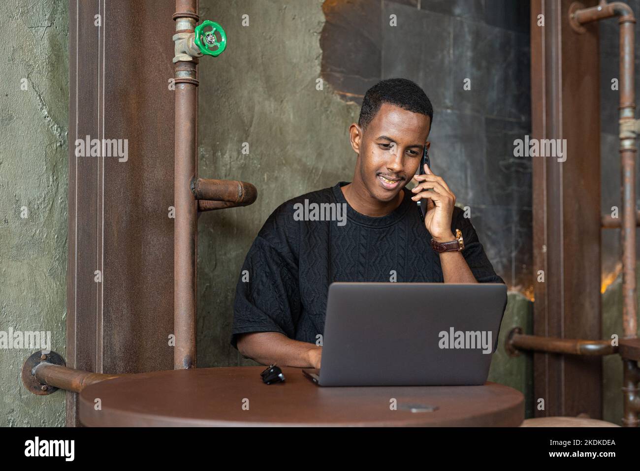 Portrait d'un beau homme noir assis et utilisant un ordinateur portable à l'intérieur Banque D'Images