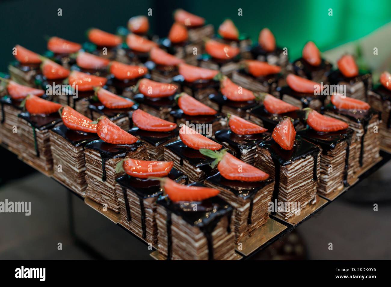 Gâteau au chocolat appétissant, coupé en morceaux carrés, décoré de tranches de fraise. Table festive pour célébrer les fêtes Banque D'Images