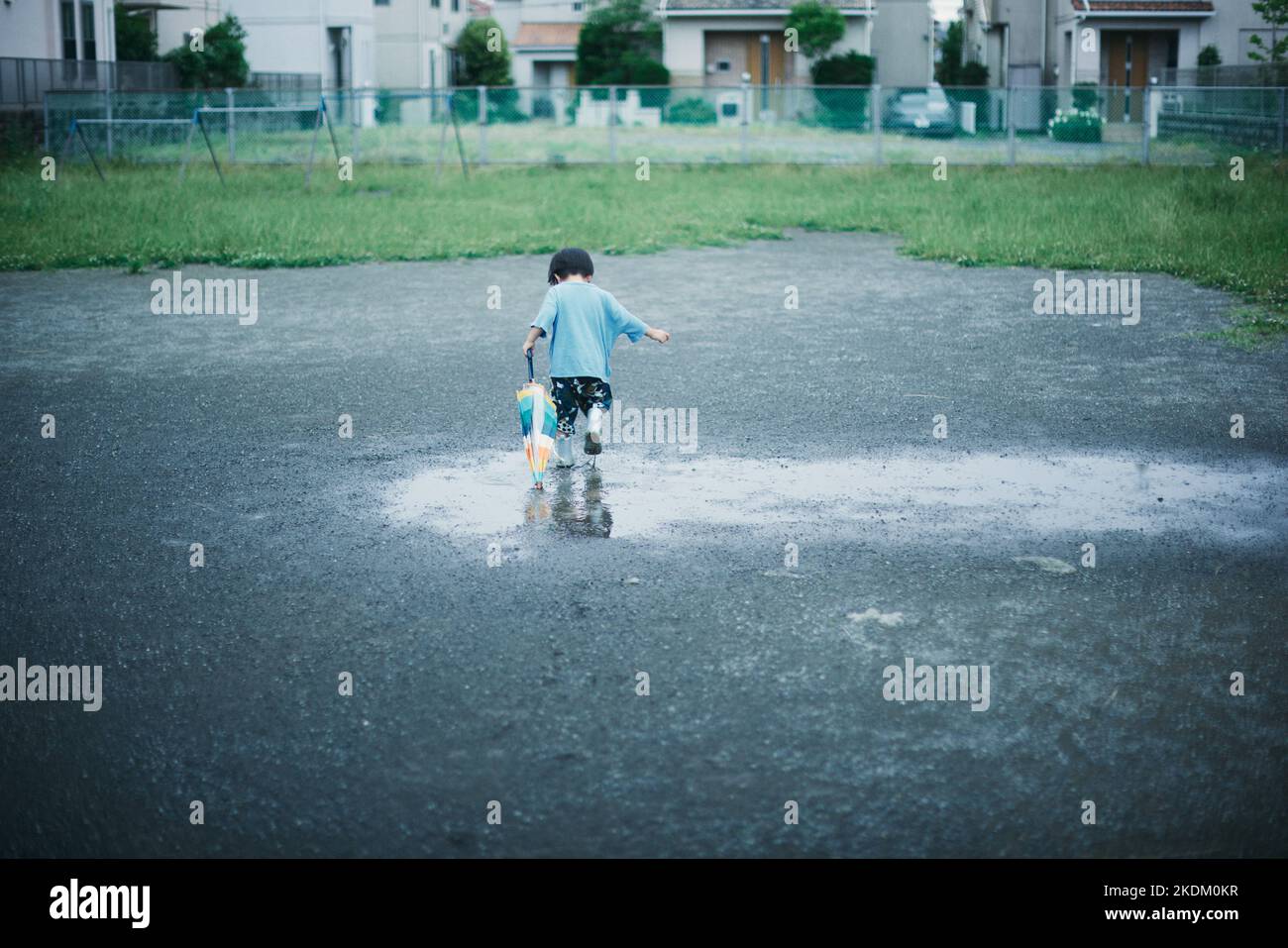 Enfant japonais jouant dehors le jour des pluies Banque D'Images