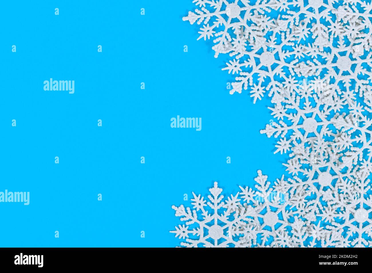 Décorations de Noël en forme de flocon de neige blanc sur le côté d'un fond bleu avec espace pour les copies Banque D'Images
