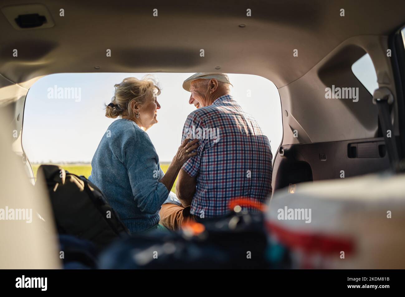 Heureux couple senior assis dans le coffre ouvert en voiture dans la nature Banque D'Images