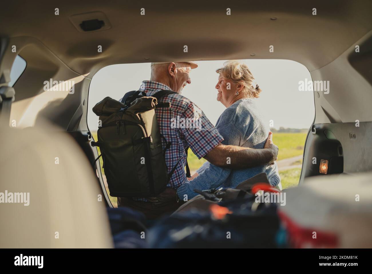 Heureux couple senior assis dans le coffre ouvert en voiture dans la nature Banque D'Images
