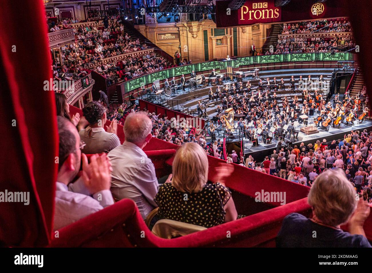 ALBERT HALL INTÉRIEUR Performance BBC Proms avec public applaudissant/clapping vu de velours rouge de luxe privée à l'auditoire et promeneurs permanent scène orchestre estrade Banque D'Images