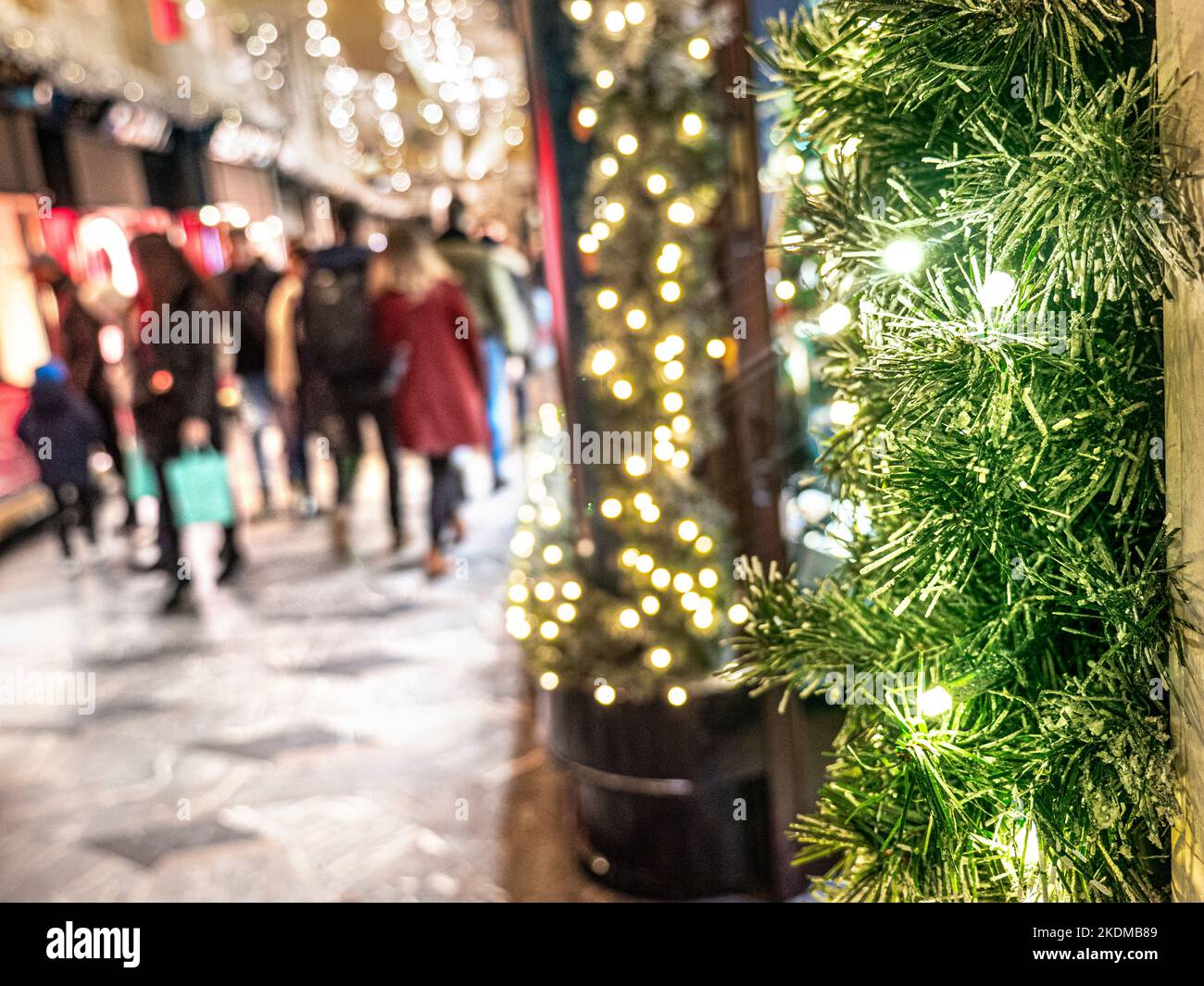 LONDON CHRISTMAS SHOPPING CONCEPT Piccadilly Burlington Arcade avec arbres et lumières festives en premier plan et des shoppers flous transportant des sacs de shopping en arrière-plan Piccadilly London UK Banque D'Images