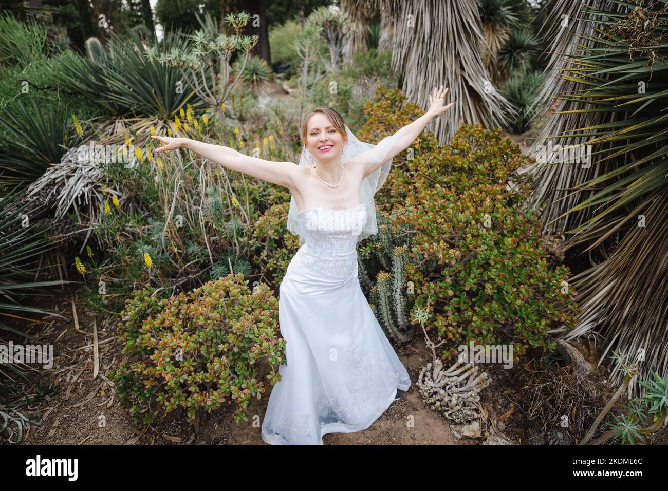 Mariée faisant des ailes d'avion avec des armes dans un jardin de Cactus Banque D'Images