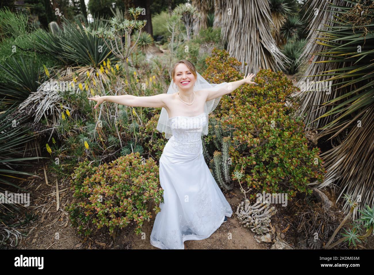 Mariée faisant des ailes d'avion avec des armes dans un jardin de Cactus Banque D'Images