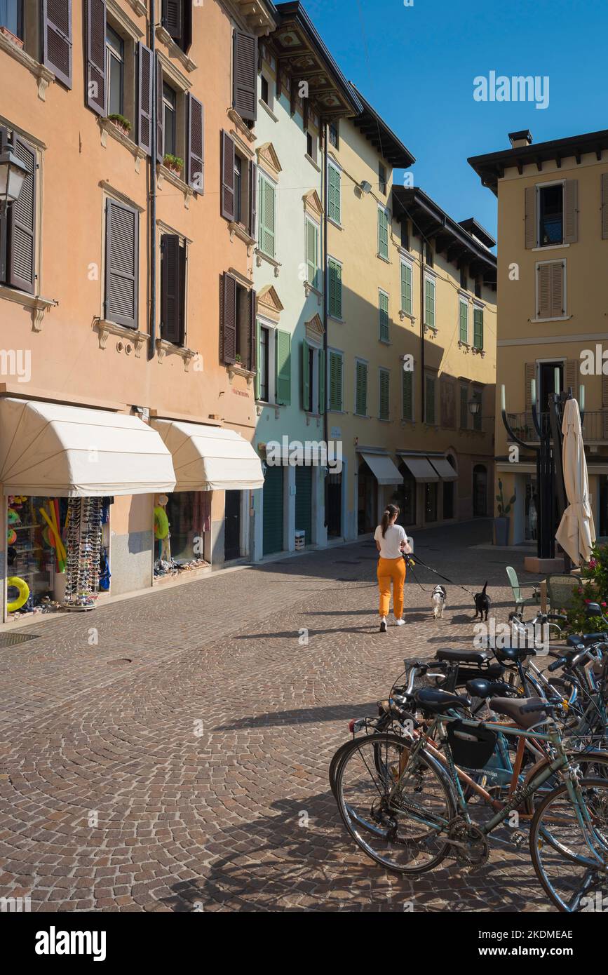 Femme marchant chien, vue arrière un matin d'été d'une jeune femme marchant ses deux chiens dans une rue pittoresque en Italie, Europe Banque D'Images