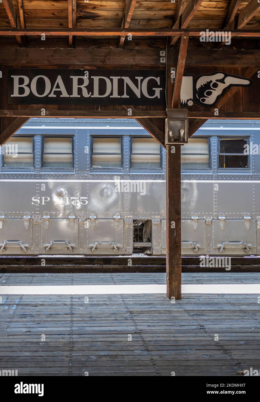 plate-forme de train en bois avec grande affiche d'embarquement indiquant aux passagers la direction dans laquelle ils doivent monter à bord du train Banque D'Images