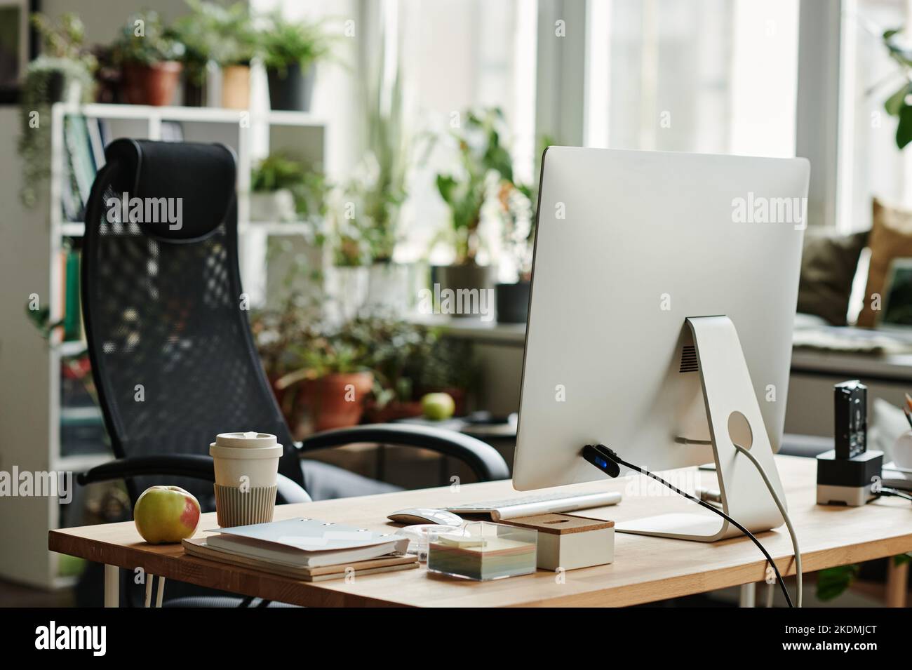 Lieu de travail moderne de ouvrier de collier blanc avec moniteur d'ordinateur, pomme fraîche et tasse de café et fauteuil noir dans l'espace de travail de collègue Banque D'Images