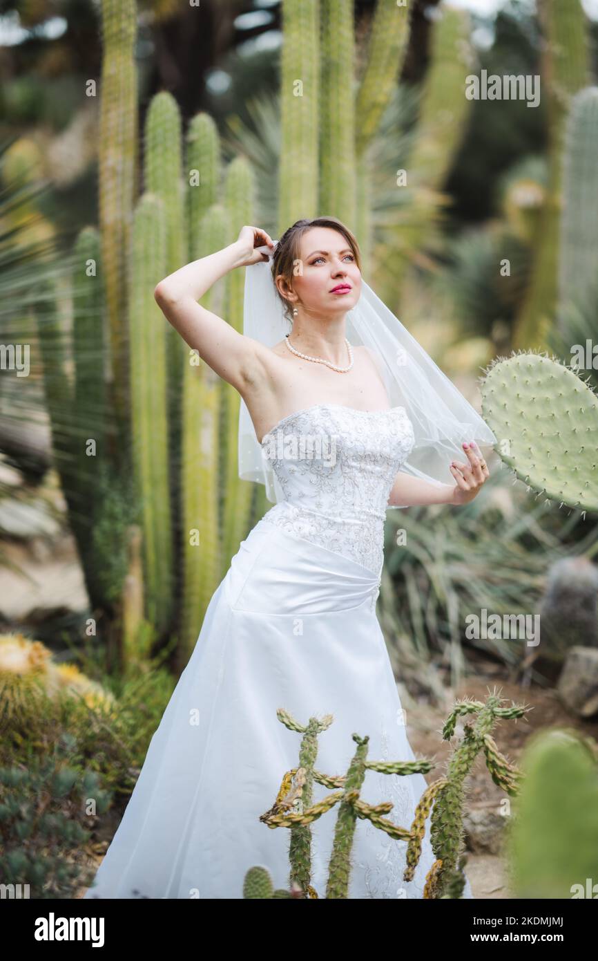 Mariée entourée de plantes de Cactus dans un jardin en fin d'après-midi Banque D'Images