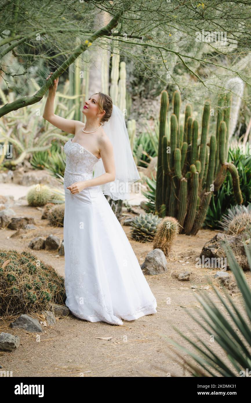 Mariée tenant une branche d'arbre dans un jardin de Cactus Banque D'Images