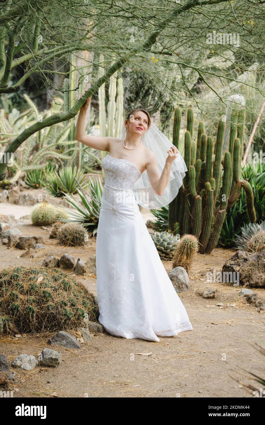 Mariée tenant une branche d'arbre dans un jardin de Cactus Banque D'Images