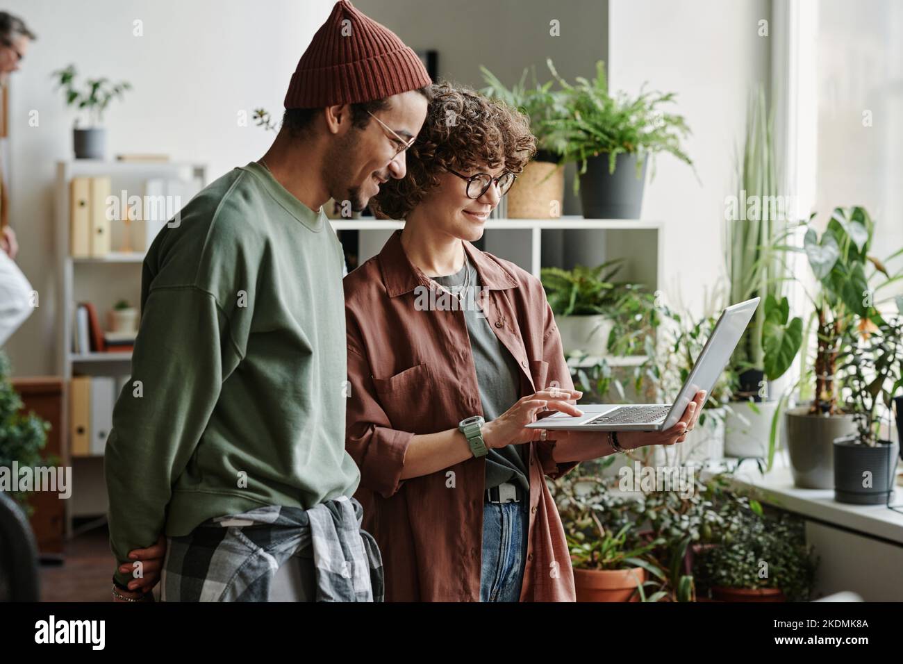 Deux jeunes développeurs de logiciels discutant de l'information en ligne et de leurs idées tout en créant un nouveau programme avec l'aide de conseils en ligne Banque D'Images