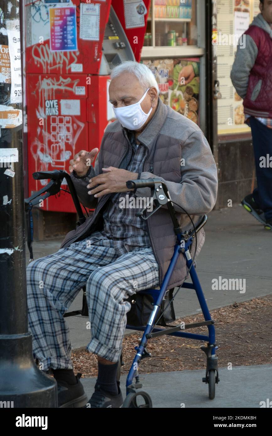 Un homme musulman plus âgé prie sur Diversity Plaza tout en étant assis sur son marcheur. À Jackson Heights, Queens, New York. Banque D'Images