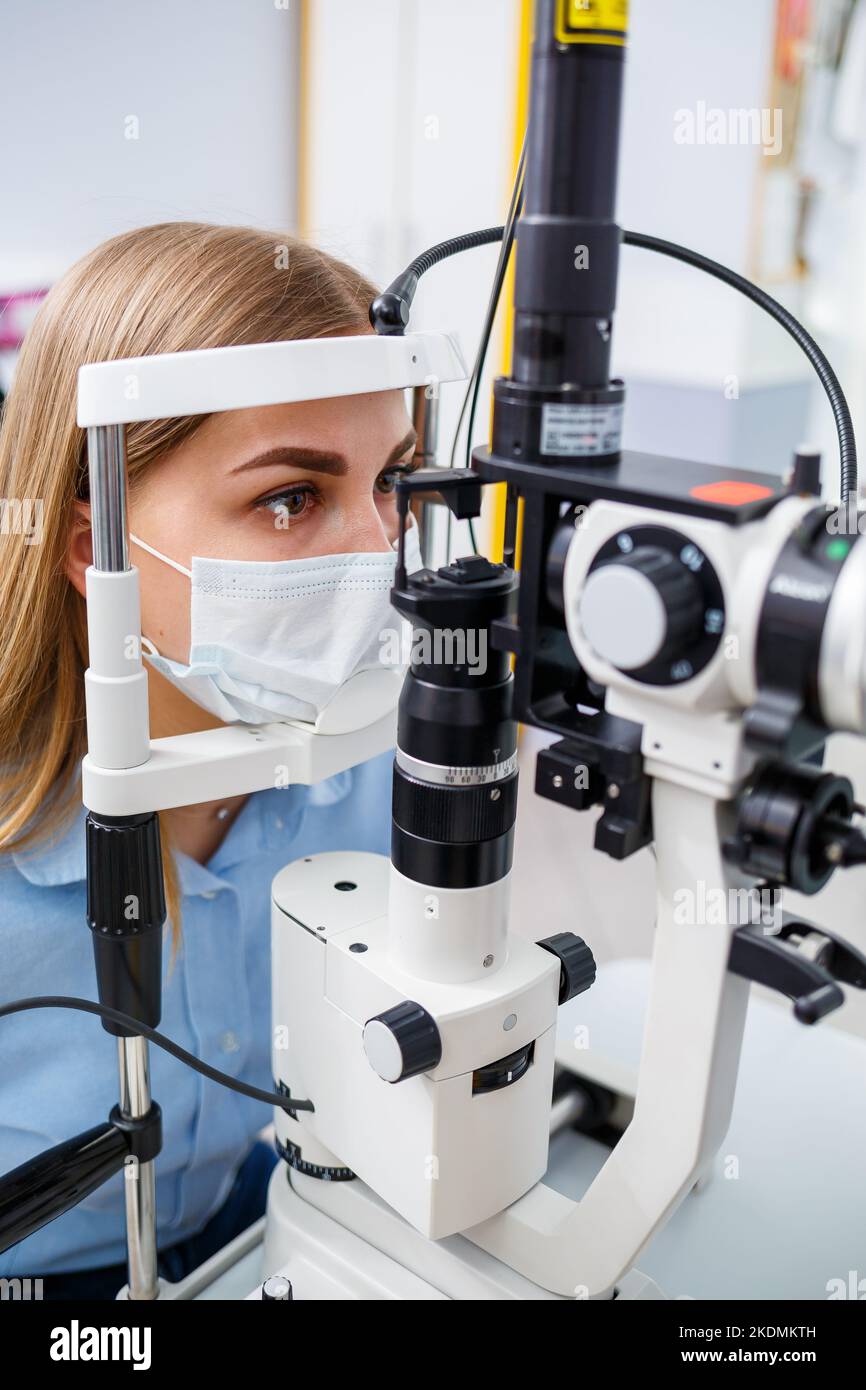 Jeune femme assise dans un fauteuil regardant la lampe fendue pendant un examen médical dans les yeux Banque D'Images
