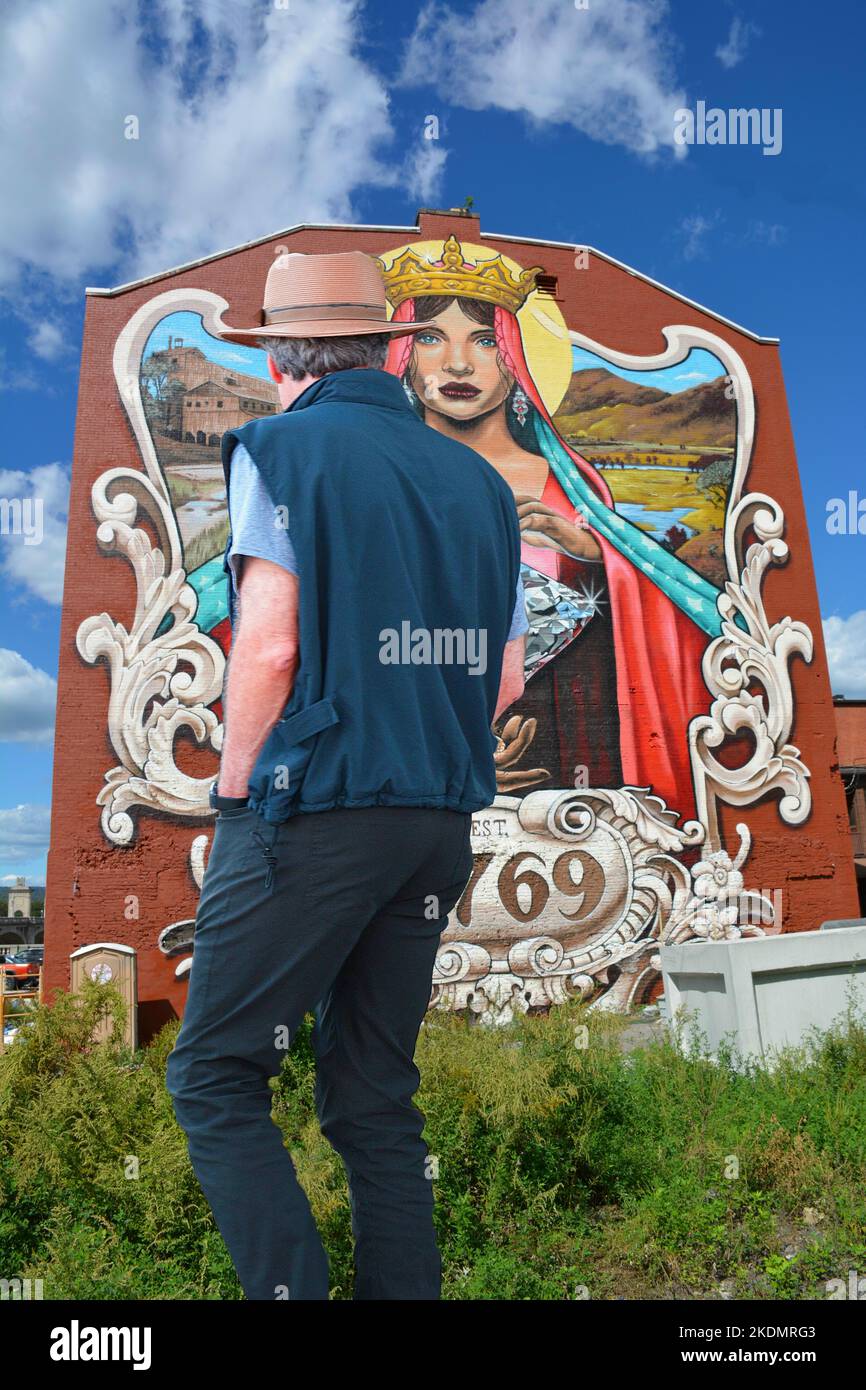 Un homme pond une énorme peinture murale à l'arrière d'un bâtiment en cours de rénovation sur River St. dans le centre-ville de Wilkes barre, Pennsylvanie. Banque D'Images