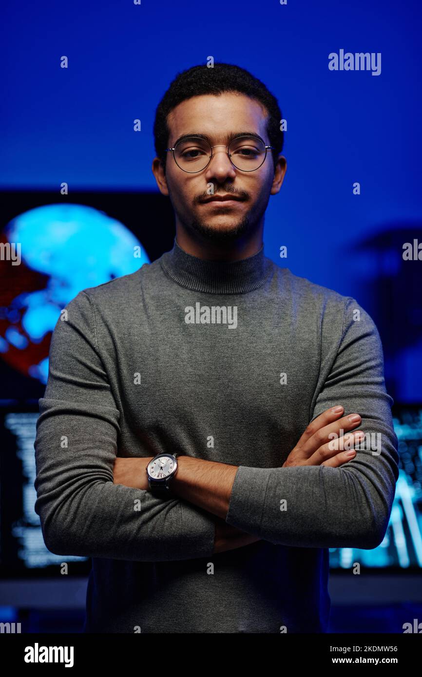 Jeune développeur de logiciels confiant ou responsable de l'assistance INFORMATIQUE en pull-over gris décontracté croisant les bras par la poitrine tout en se tenant devant la caméra Banque D'Images