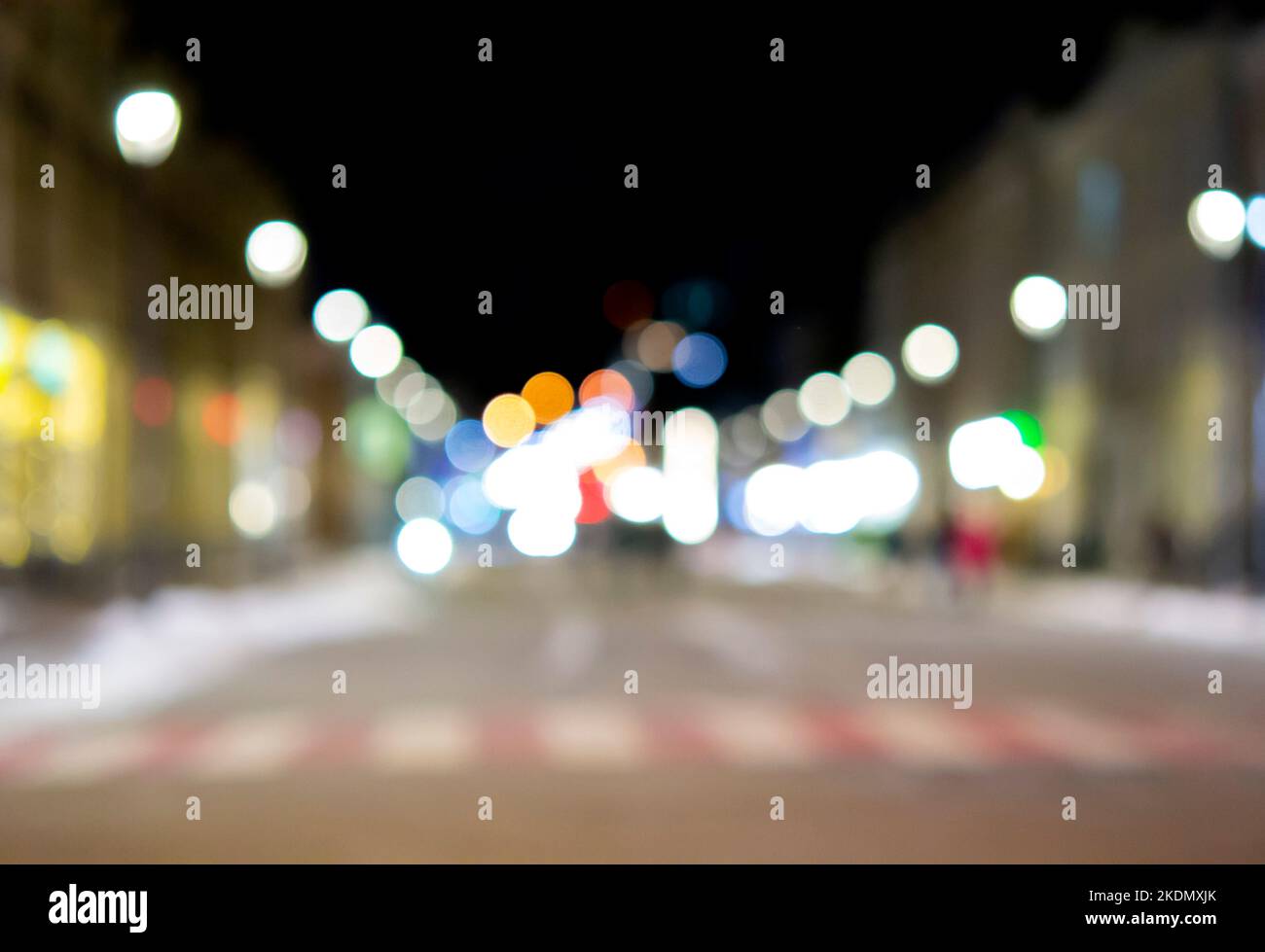 Arrière-plan flou. Ville de nuit. Silhouette floue des bâtiments, taches de bokeh de lanternes brillantes, silhouettes floues des personnes marchant dans la rue le soir. Place de la ville, ciel nocturne noir Banque D'Images