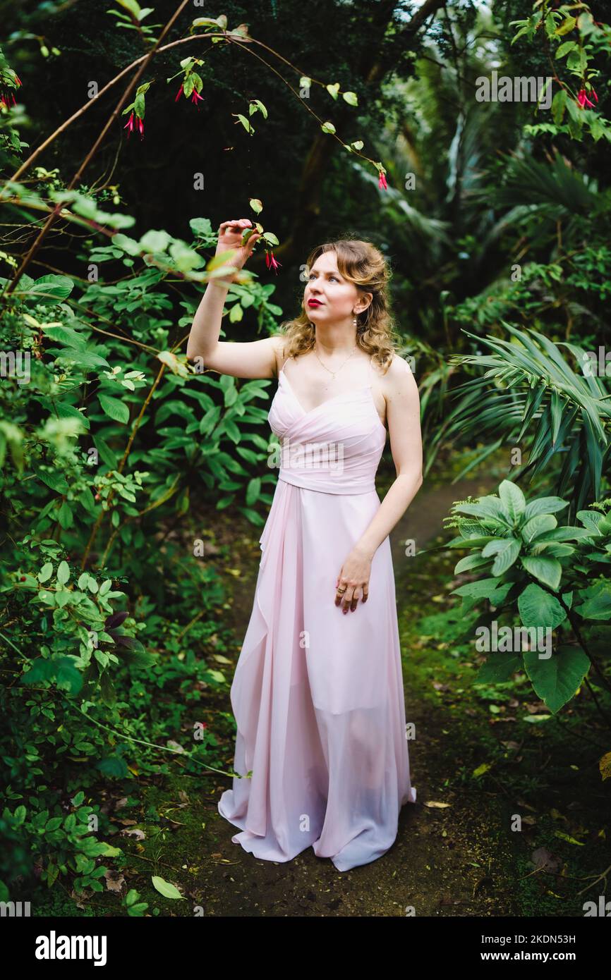 Femme portant un Rose Gown visitant un jardin idyllique Banque D'Images