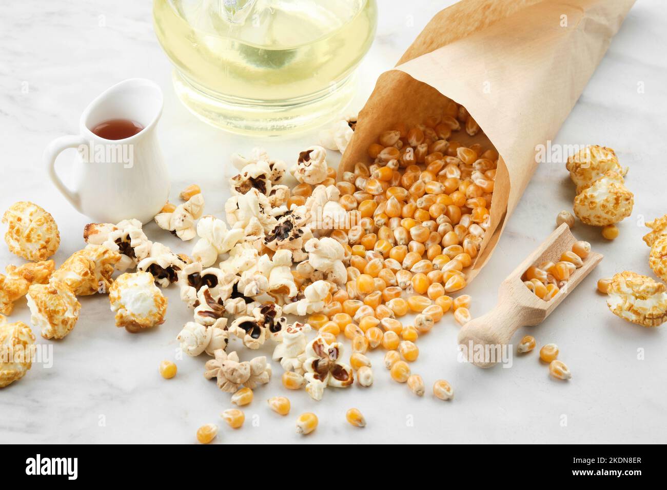 Pop-corn, grains de maïs séchés, sauce caramel et bouteille d'huile sur la table de cuisine. Banque D'Images