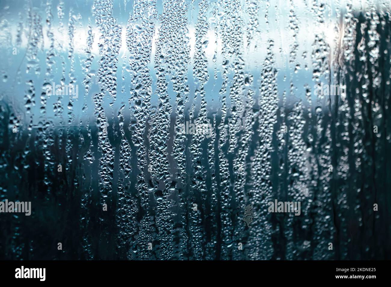 Texture du verre embué en hiver. Gouttes d'eau congelées au soleil sur la fenêtre. Aube à l'extérieur de la fenêtre. Arrière-plan abstrait. Mise au point sélective. Banque D'Images