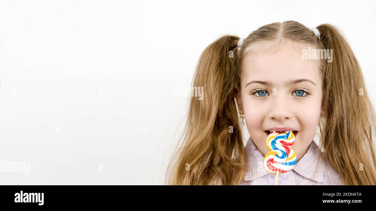 Belle fille avec les yeux bleus mangeant la lylipop isolé sur blanc Banque D'Images