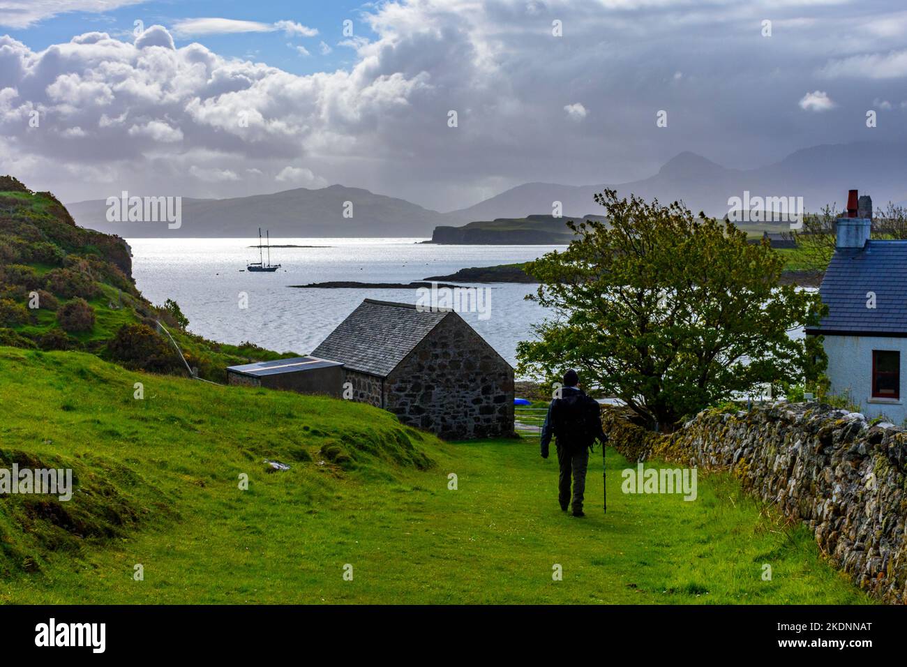 Un marcheur qui regarde le port de Canna et l'île de Sanday jusqu'à l'île de Rum, du village de A' Chill, île de Canna, Écosse, Royaume-Uni Banque D'Images