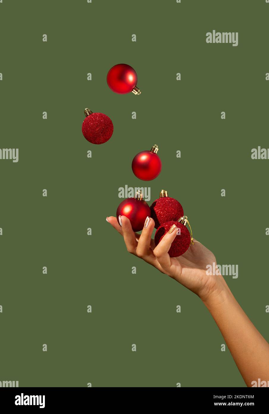 Les boules de Noël juglant à la main d'une belle femme sur fond vert foncé. Concept de vacances minimal. Bonne Année. Copier l'espace. Banque D'Images