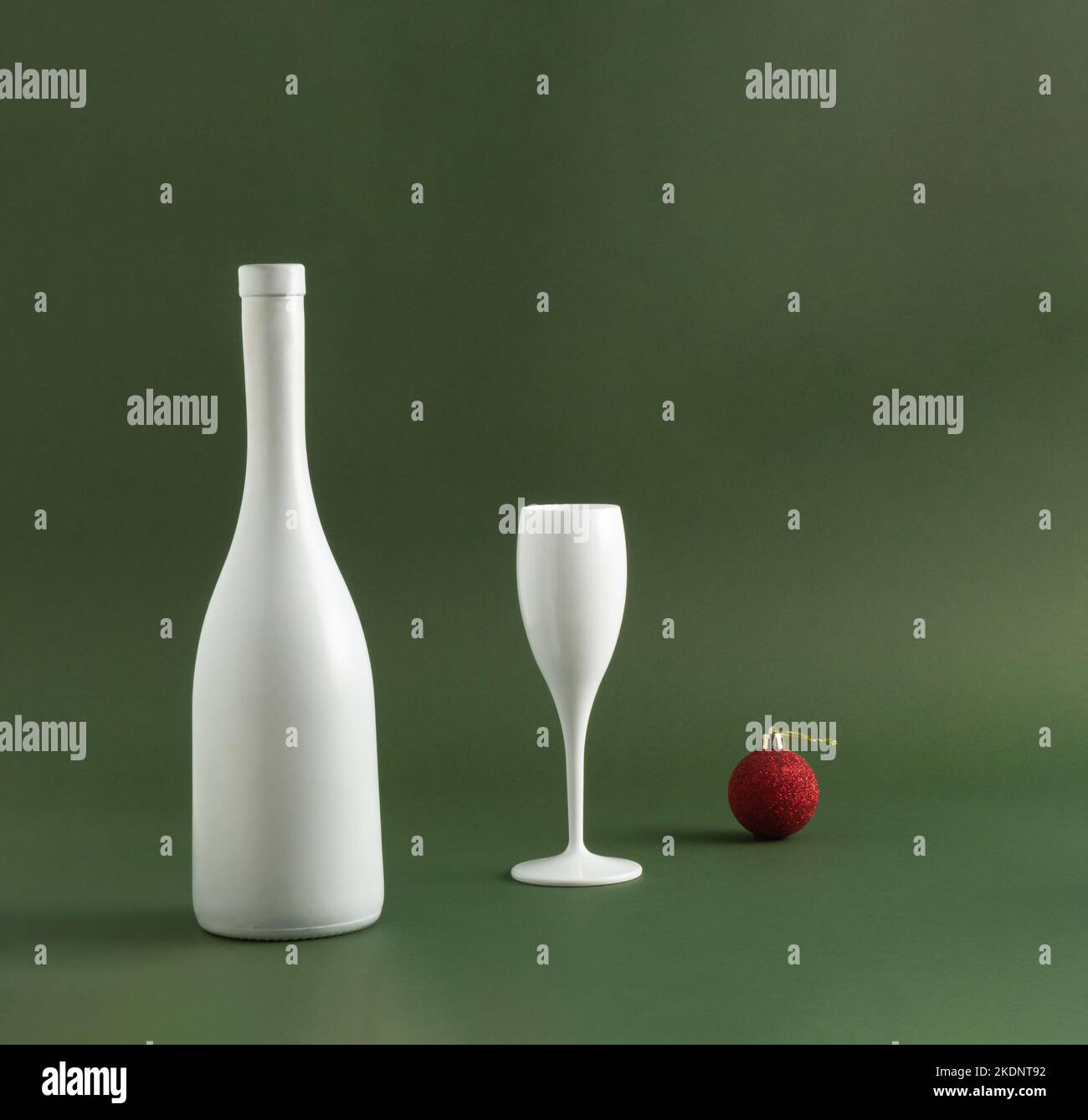 Bouteille de vin blanc, verre de vin et boule de Noël rouge sur fond vert foncé. Concept de fête minimal. Idée de célébration du nouvel an et de Noël. Copie s Banque D'Images