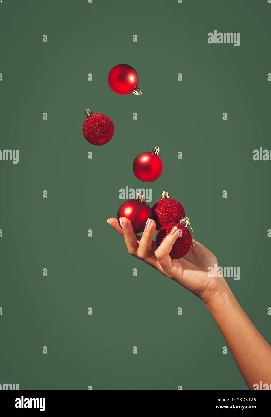 Les boules de Noël juglant à la main d'une belle femme sur fond vert foncé. Concept de vacances minimal. Bonne Année. Copier l'espace. Banque D'Images