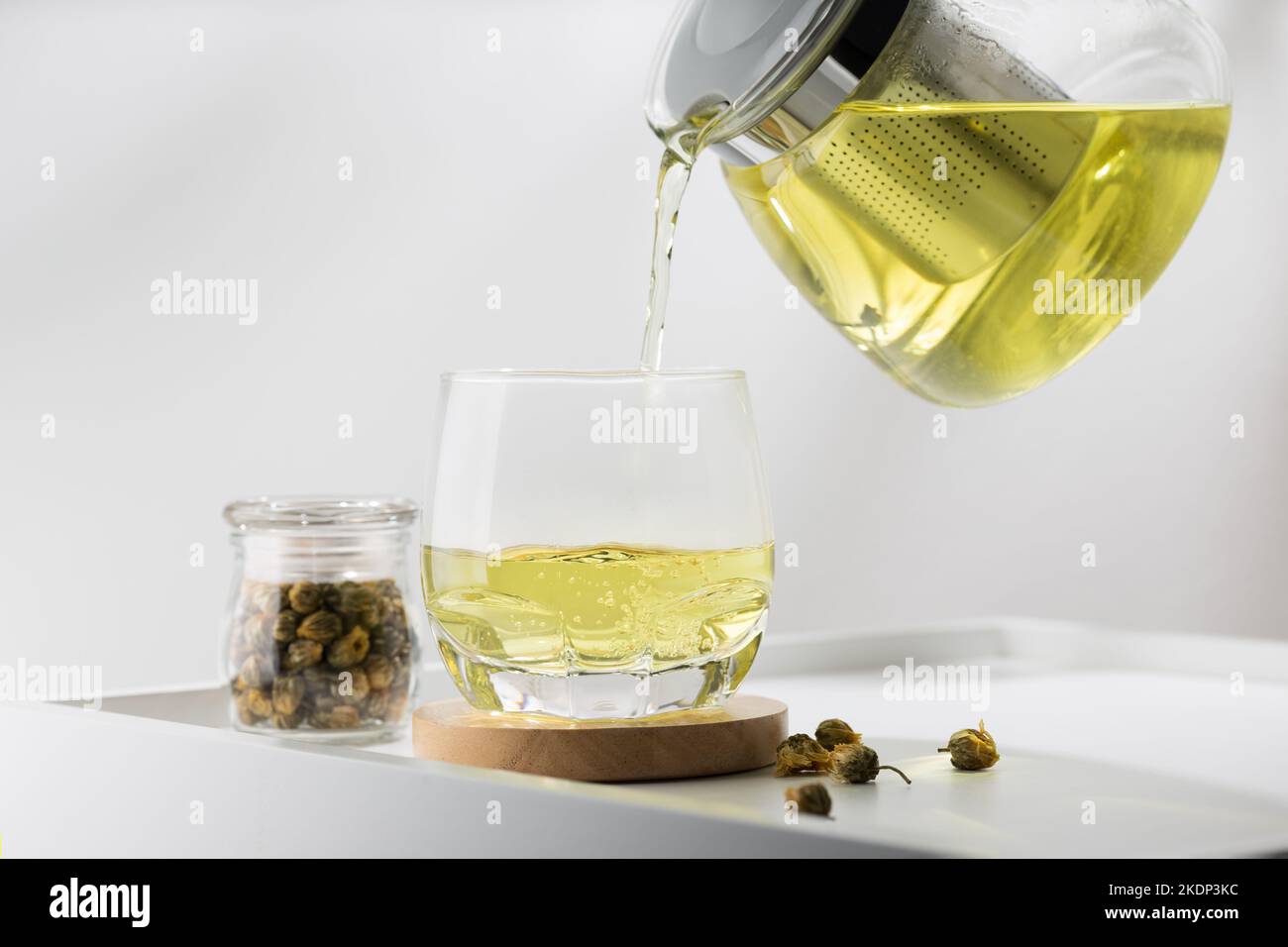 Verser le thé de chrysanthème dans le verre de la table blanche Banque D'Images