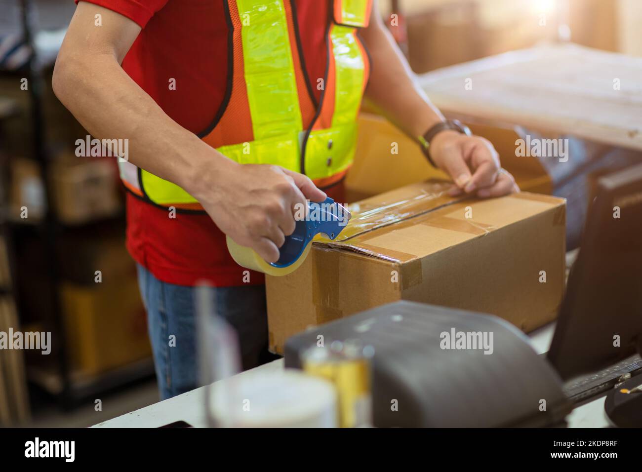 l'employé du ruban adhésif d'emballage des produits d'étanchéité préparation de la boîte pour l'expédition de livraison au client de commande en ligne. Banque D'Images