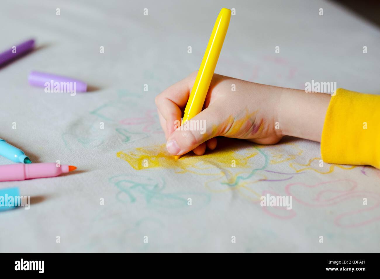 La main de l'enfant dessin avec un feutre sur la sellerie du canapé. Tissus de mobilier. Concept de nettoyage Banque D'Images