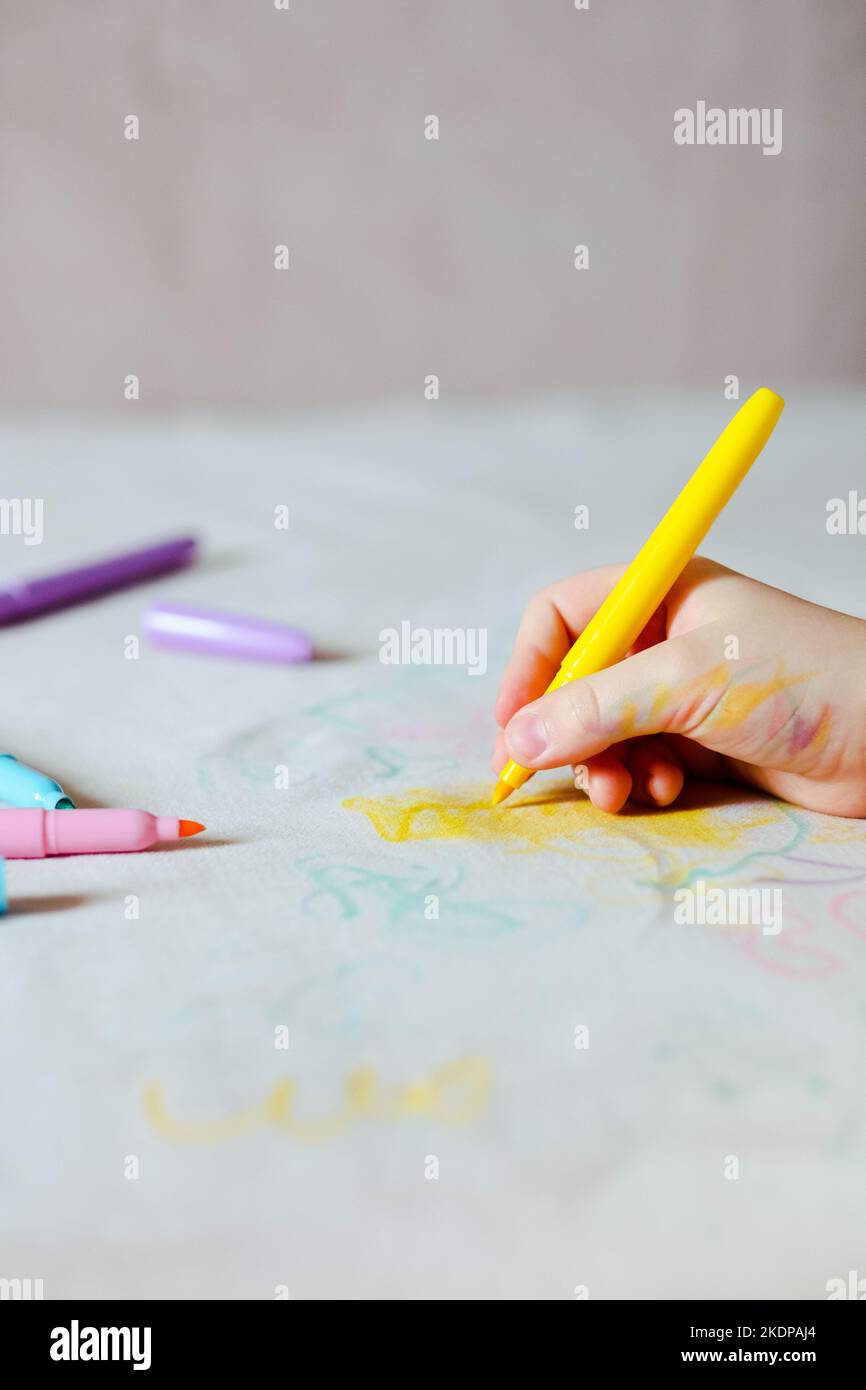 La main de l'enfant dessin avec un feutre sur la sellerie du canapé. Tissus de mobilier. Concept de nettoyage Banque D'Images