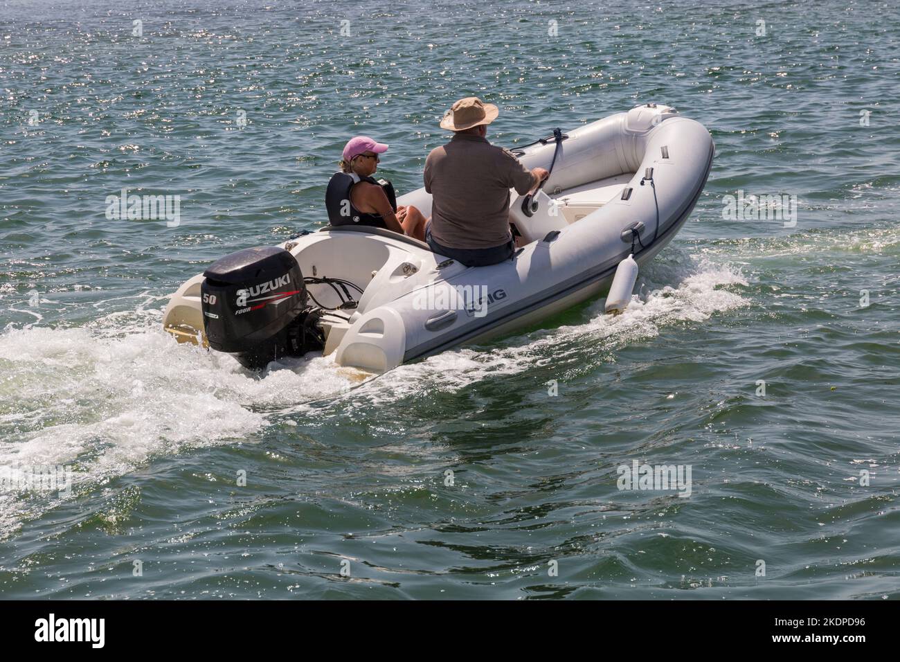 Couple à bord d'un bateau rigide gonflable de Brig, EN voiture jusqu'à l'entrée du port de Christchurch, connu sous le nom de The Run, Mudeford, Dorset UK en juin Banque D'Images