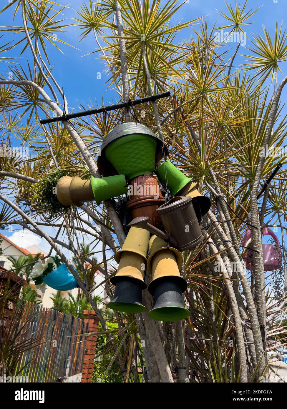 Gros plan vertical d'une figurine de jardin originale faite de pots empilés, accrochés de manière créative à un arbre, ajoute charme et fantaisie à la décoration extérieure Banque D'Images