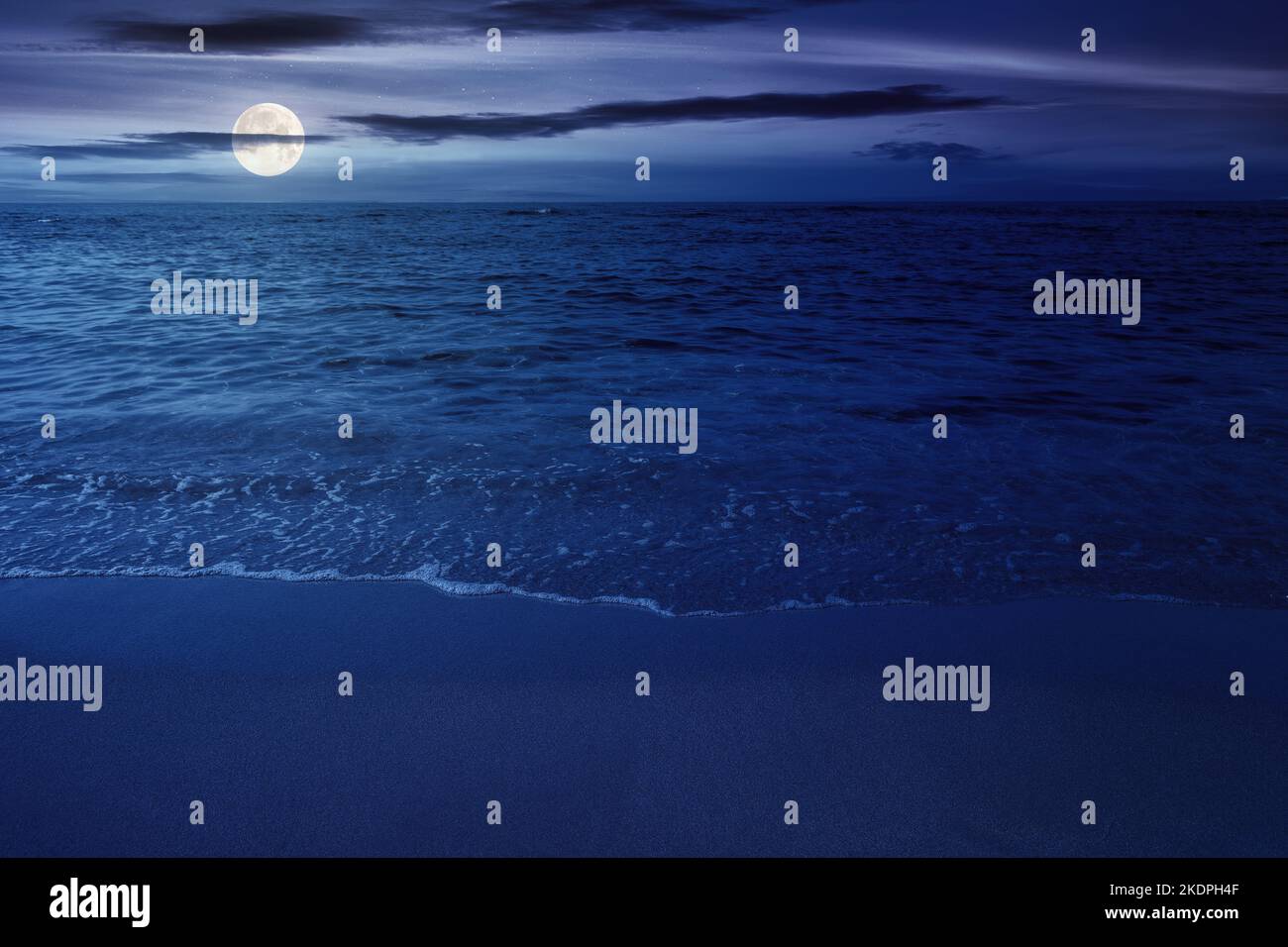 paysage nocturne à la mer. vagues calmes lavant la plage de sable en pleine lumière de lune. eau transparente et ciel bleu vif Banque D'Images