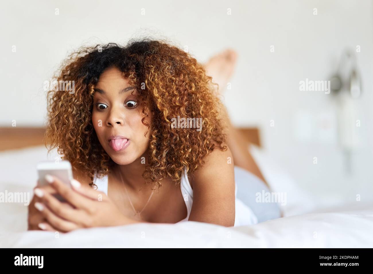 Prenez cet Internet lent... une jeune femme qui envoie des SMS en étant allongé sur son lit. Banque D'Images