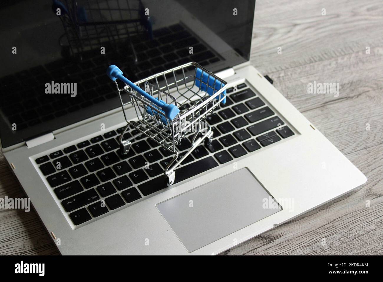 Un ordinateur portable et un mini chariot à provisions sur une table en bois. Concept d'achat en ligne Banque D'Images