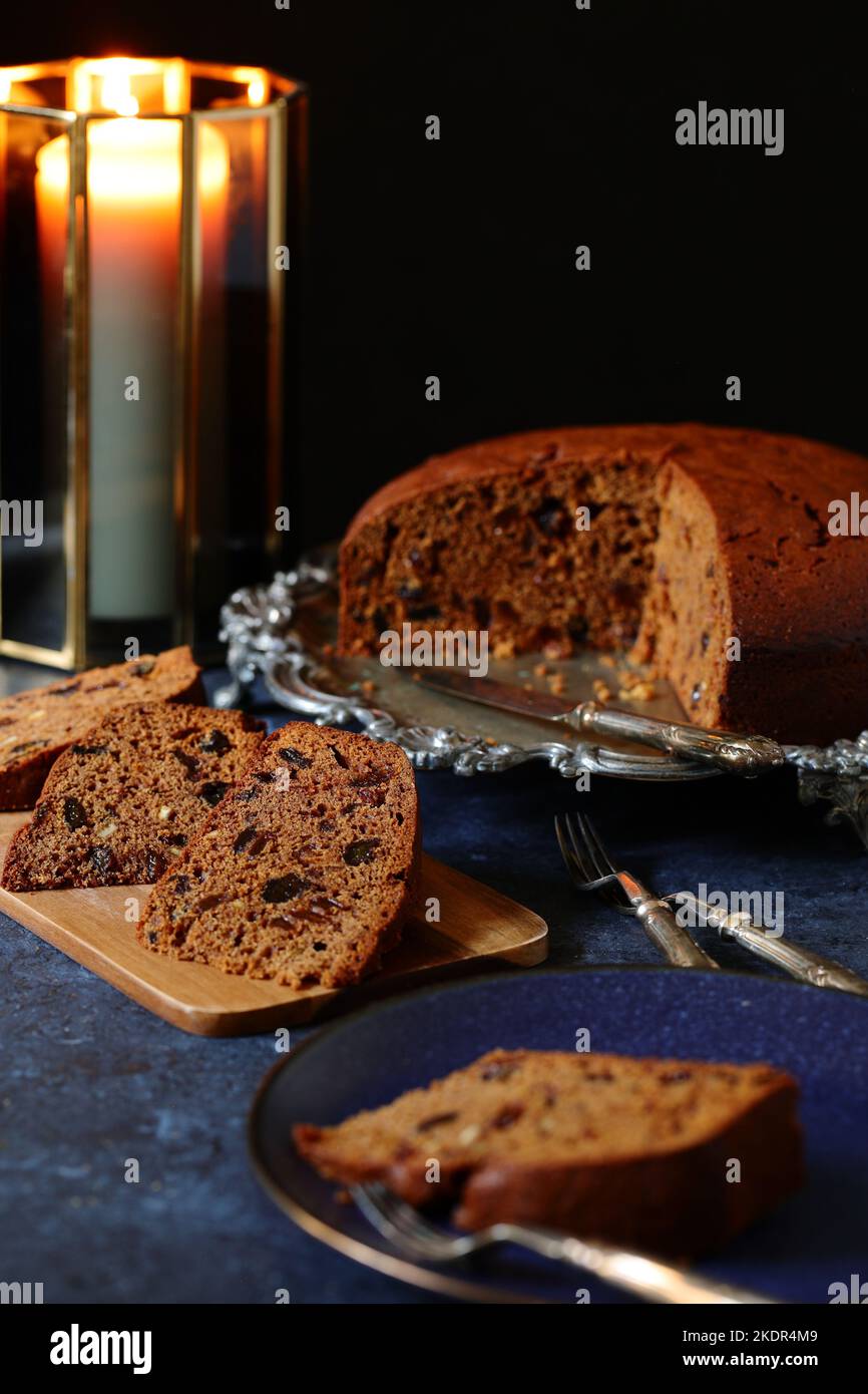 Des tranches de fruits riches maison traditionnels et un gâteau Guinness sur un plateau argenté décoratif vintage avec des fourchettes à dessert décoratives et des bougies Banque D'Images