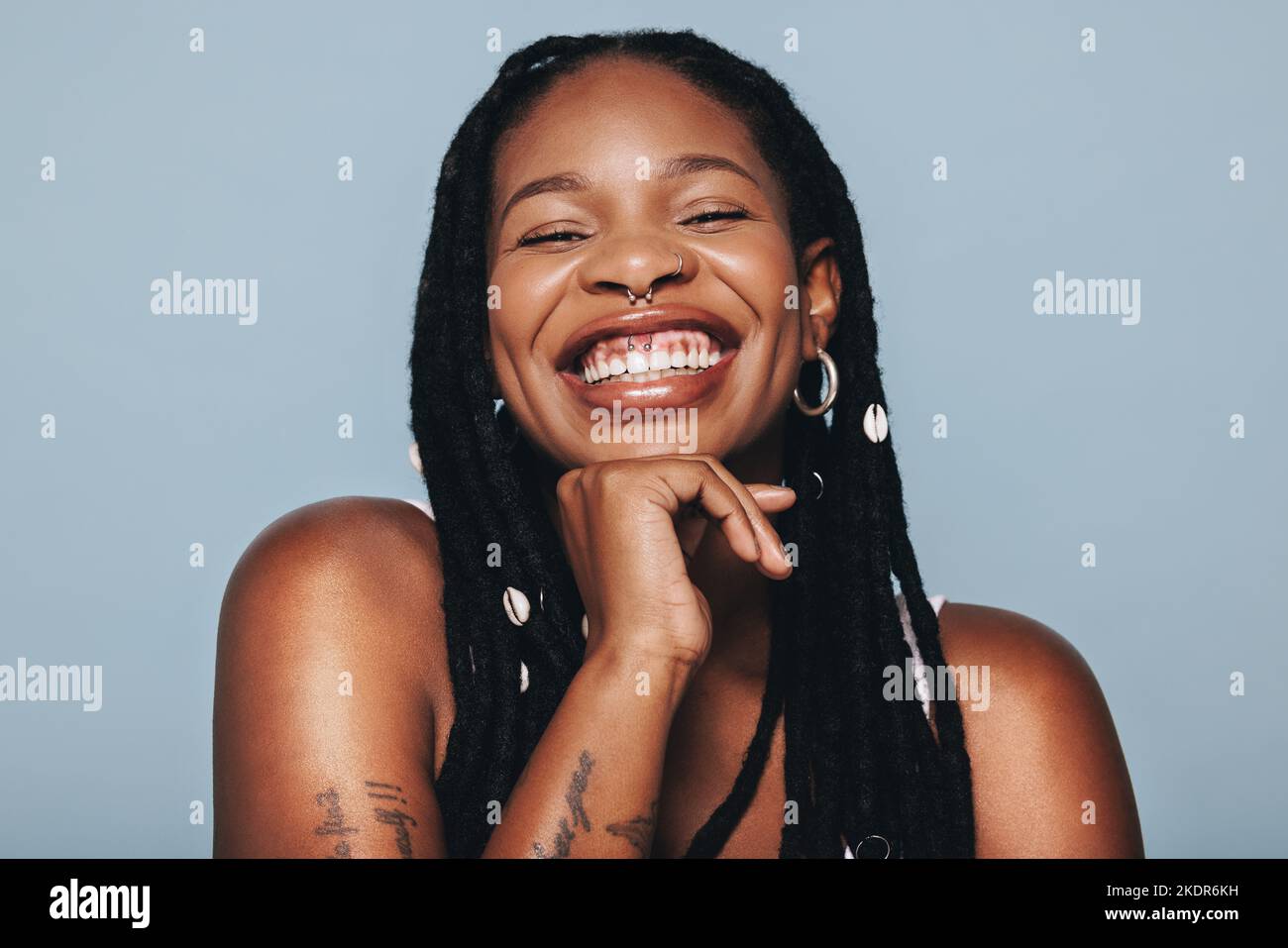 Une femme heureuse avec des piercings de visage souriant à l'appareil photo dans un studio. Jeune femme noire se sentant confiante en elle-même. Banque D'Images