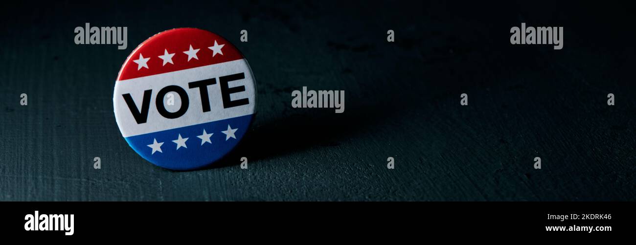 Un badge de vote pour l'élection des États-Unis sur une surface gris foncé, avec un espace vide sur la droite, dans un format panoramique à utiliser comme bannière Web ou Banque D'Images