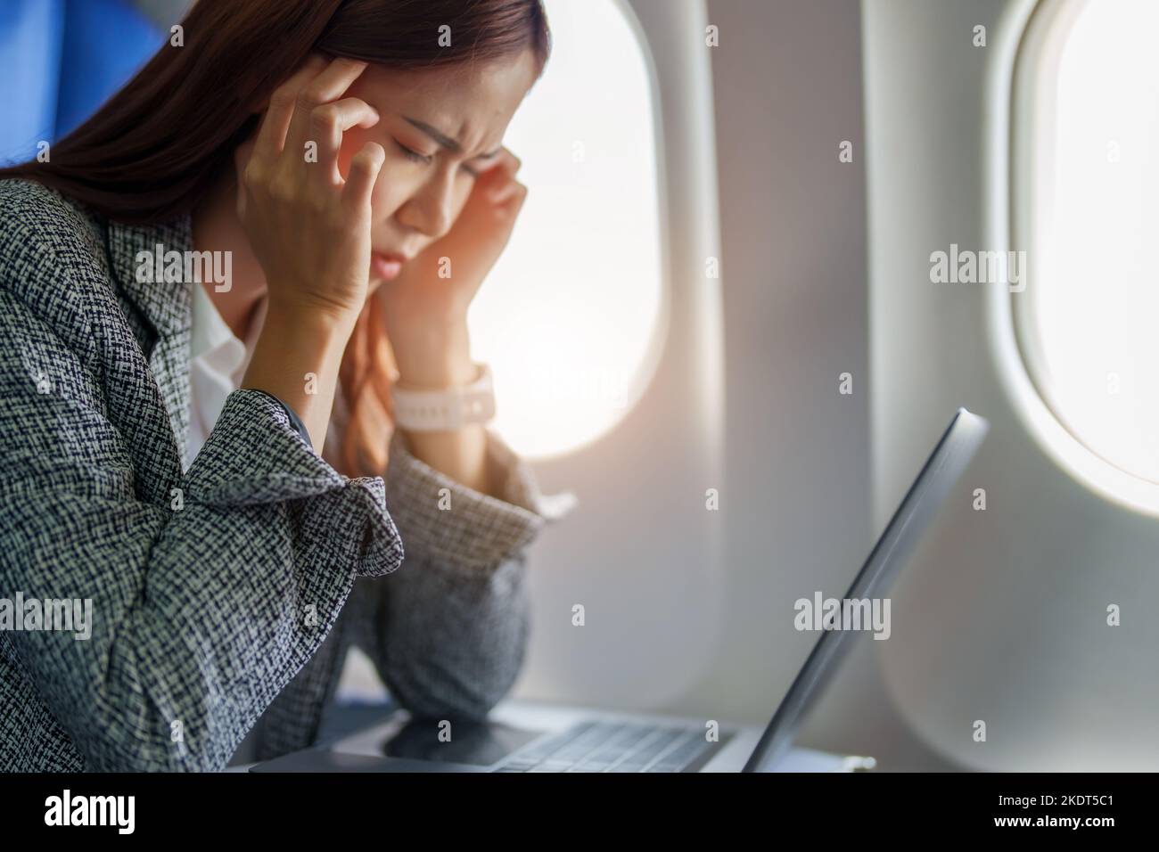Le portrait d'une femme d'affaires ou d'un entrepreneur asiatique réussi en costume formel sur un avion assis en classe affaires montre un réfléchi et stressé Banque D'Images