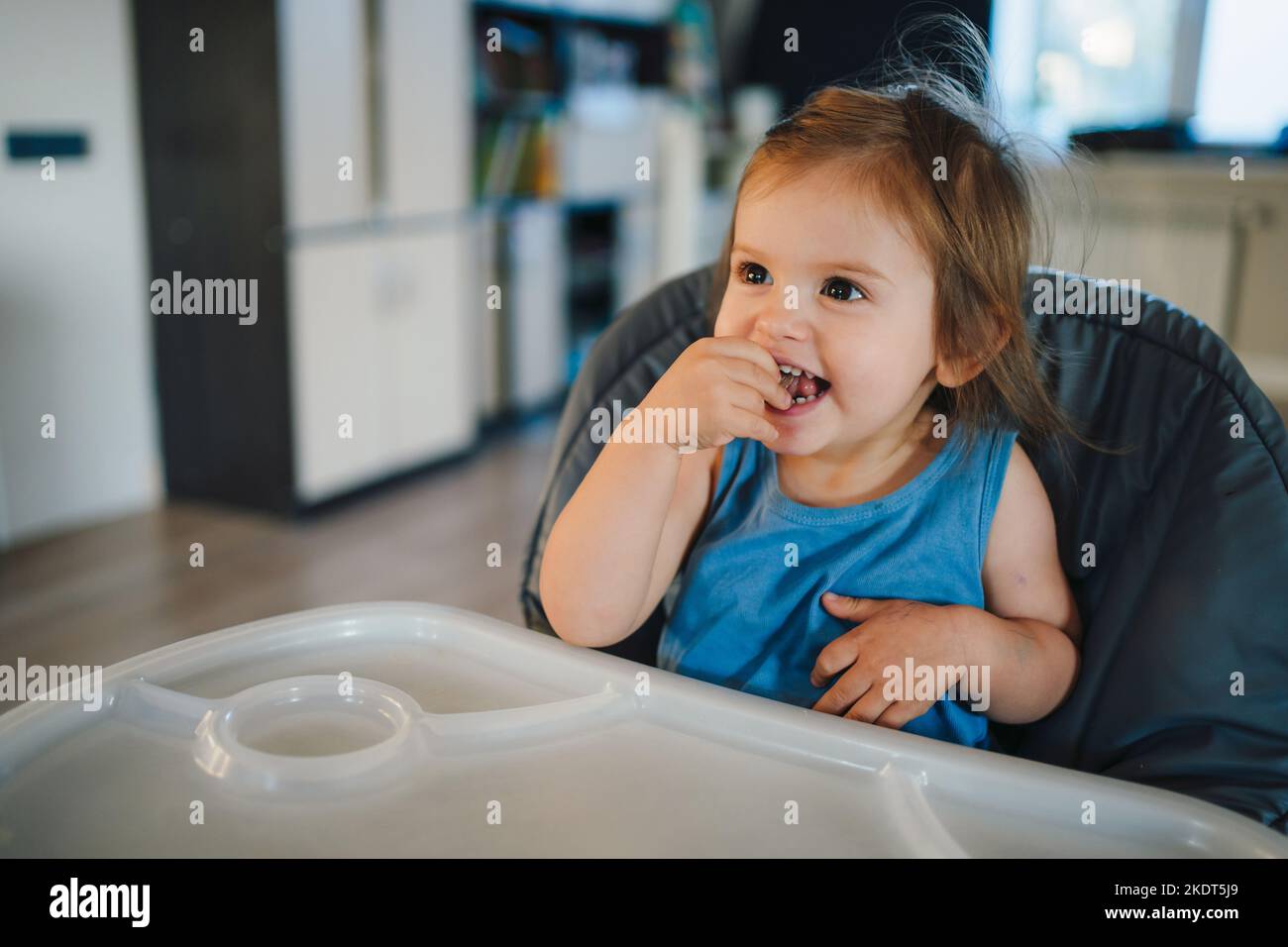 Petit garçon assis dans une chaise haute et en riant en attendant le repas. Famille amusante. Une alimentation saine. Parent, enfant. Banque D'Images