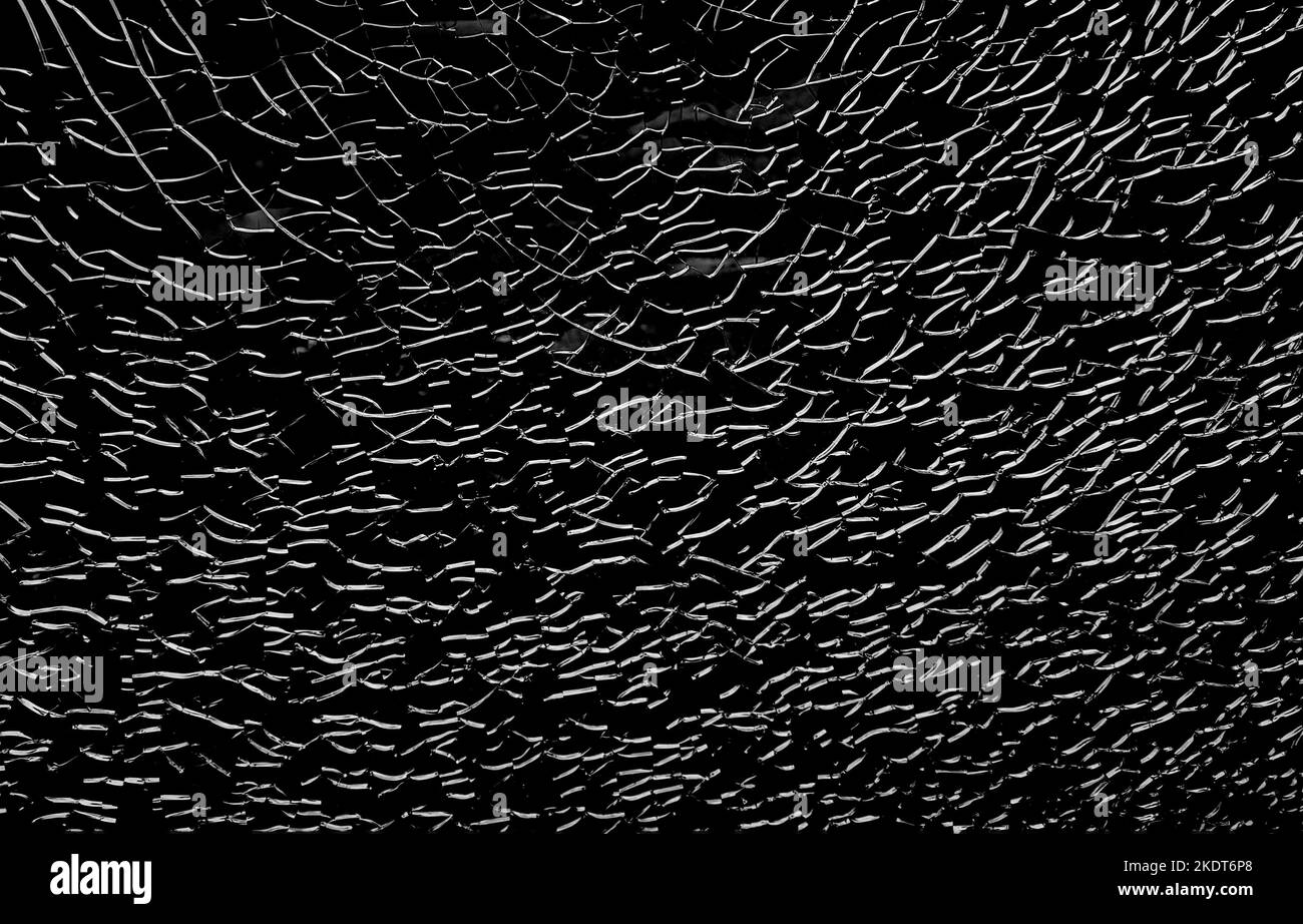 Verre cassé avec des fissures blanches. Fenêtre abstraite fendue sur noir. Banque D'Images