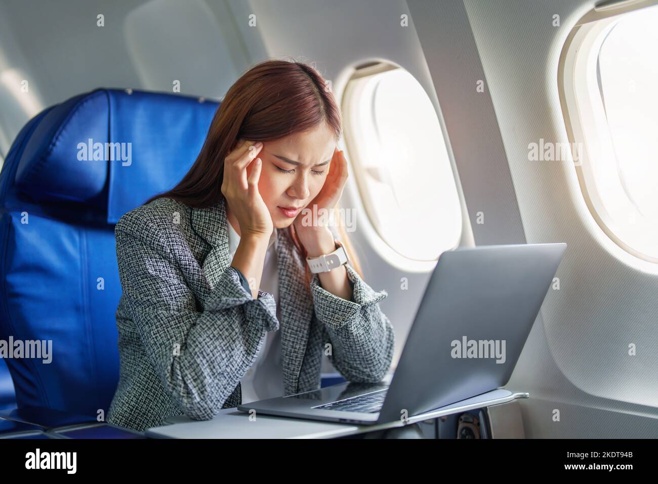 Le portrait d'une femme d'affaires ou d'un entrepreneur asiatique réussi en costume formel sur un avion assis en classe affaires montre un réfléchi et stressé Banque D'Images