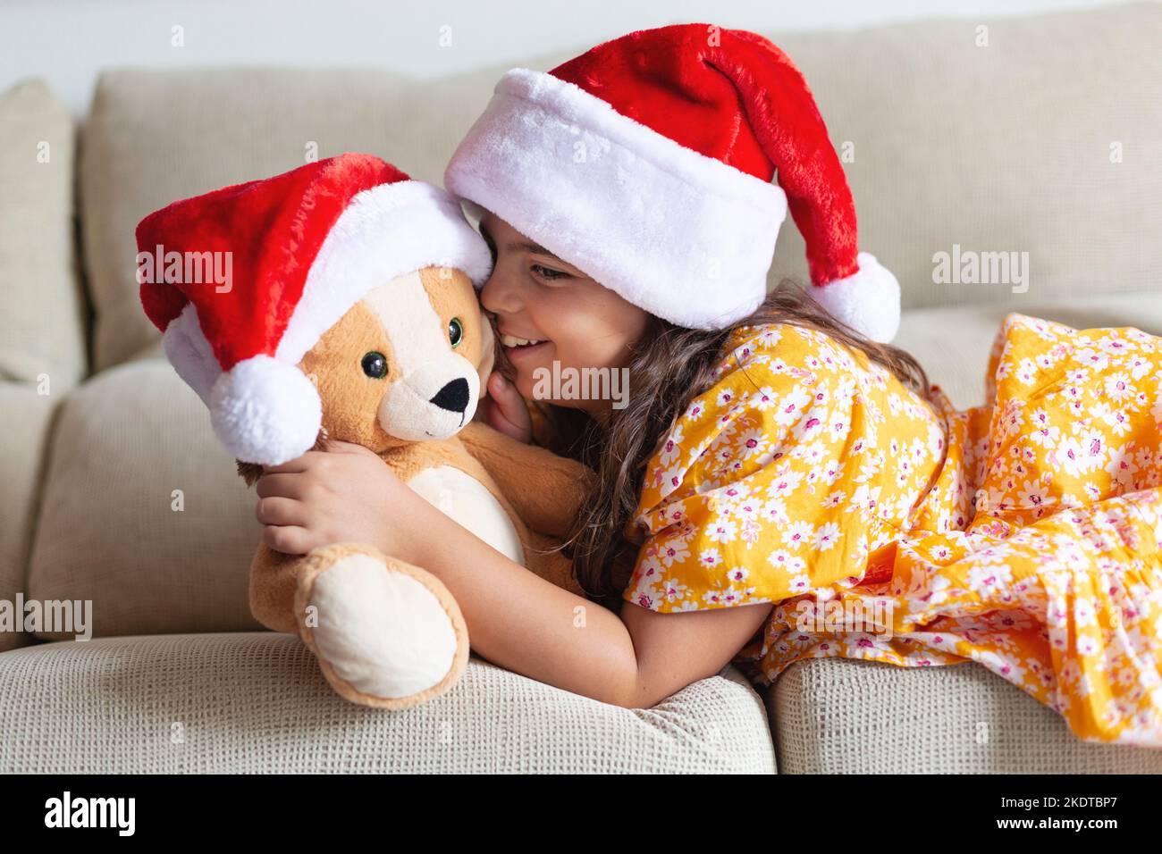 Petite fille caucasienne jouant avec son ours en peluche. Noël à la maison. Banque D'Images